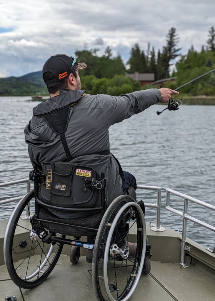 One person casting their fishing rod across the water from a platform while sitting in a wheelchair